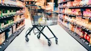 Shopping cart in well stocked aisle which leads to an increase sales in retail grocery store.